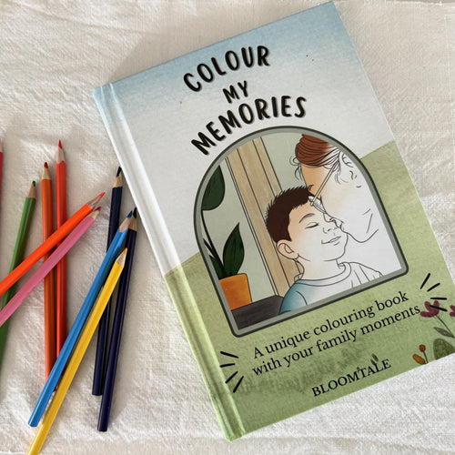 "Colour My Memories" – Personalised colouring book with real family moments, hardcover edition by Bloomtale. Photo shows the book surrounded by colourful pencils on a soft background, highlighting the warm, emotional tone of the product.